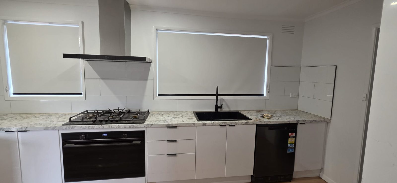 Renovated modern white kitchen with stone-look benchtop and black tapware in Thomastown, Melbourne