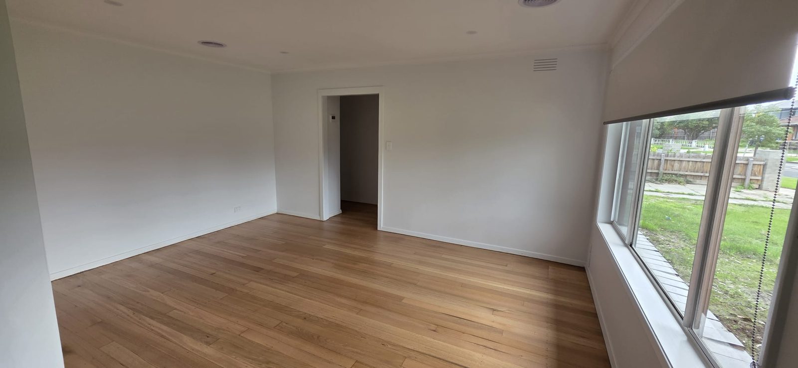 Freshly painted lounge room with polished timber floors and large window after renovation in Thomastown